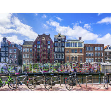 This city photo wallpaper shows the beautiful flower market next to a canal in Amsterdam The bright colors of this photo will be a great decoration!